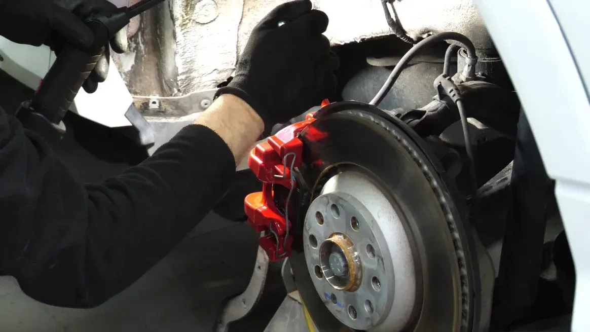 Technician Inspecting Brake Rotor and Caliper Technician Inspecting Brake Rotor and Caliper