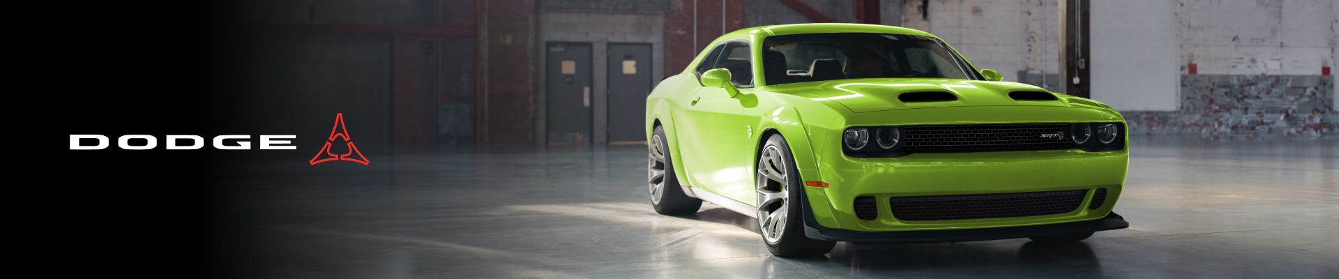 A green Dodge Challenger parked in a warehouse