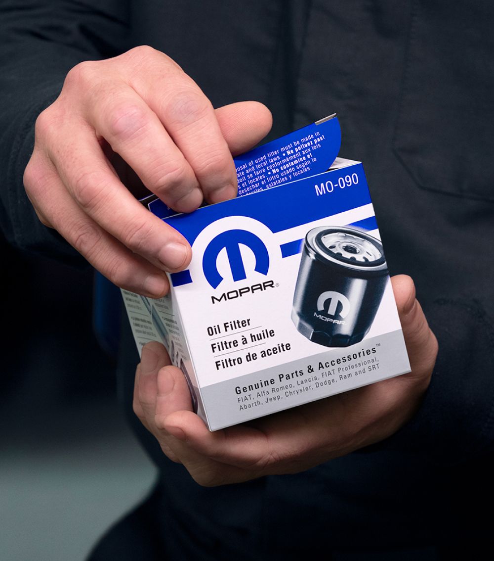 Close-up of hands opening a Mopar oil filter box