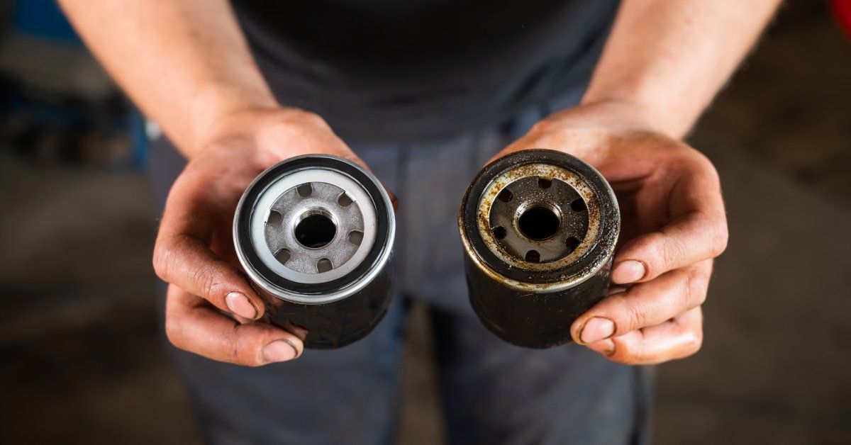A person is holding two car oil filters in their hands. One filter is clean and the other filter is dirty.