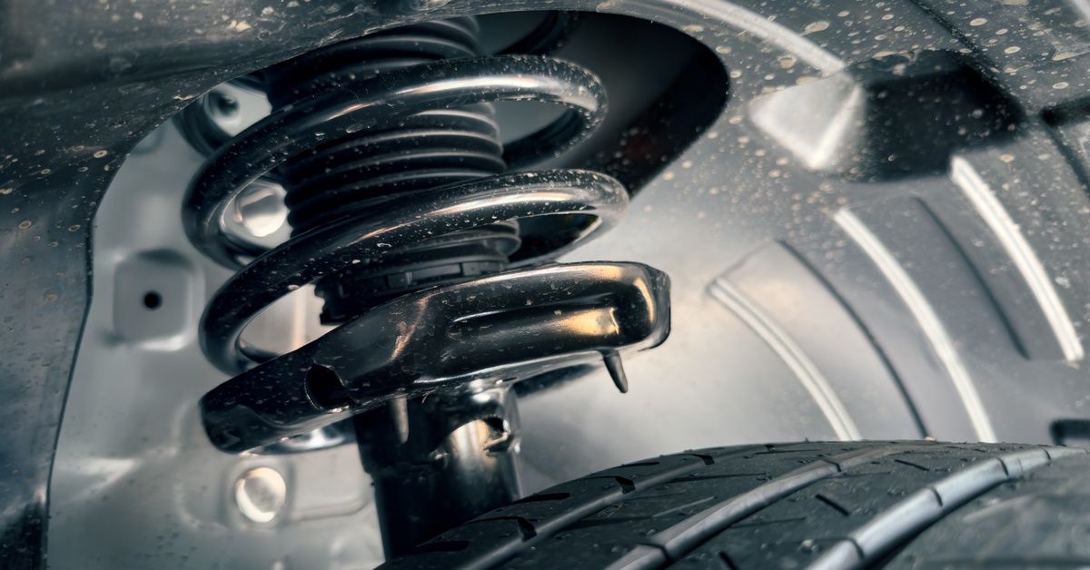 Coil springs, shocks, and struts attached to the underside of a vehicle. The tire attached to the components is clean.
