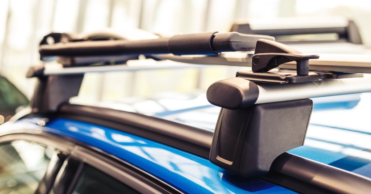 A roof rack for cargo is installed on top of a bright blue car that is outside. The roof rack is empty.